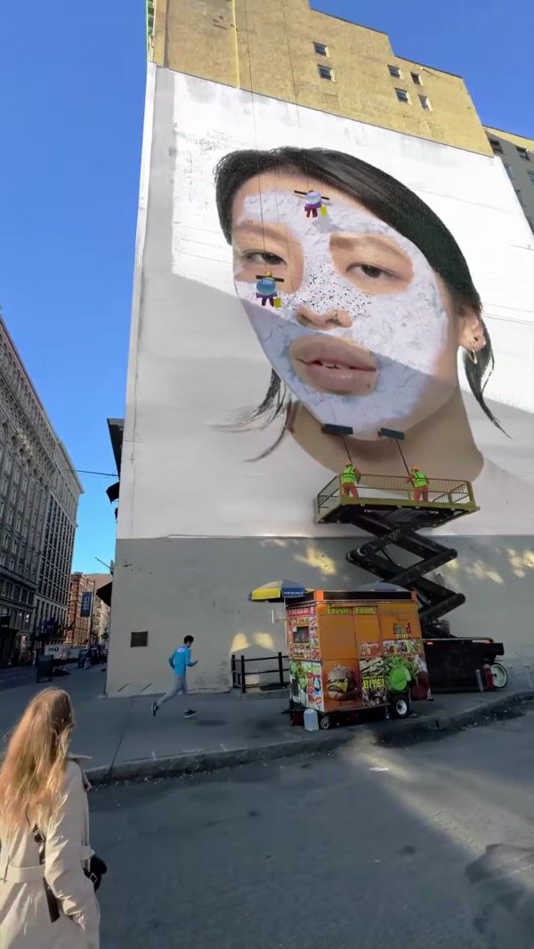 Benefit Workers Cleaning Woman’s Face on Mural