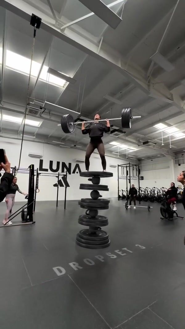 Adidas Woman Balancing on Piled Weight Plates