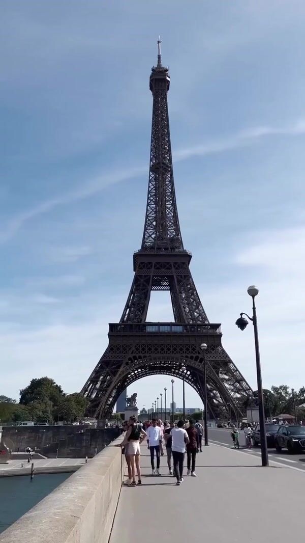 Rains Giant Blue Duffle Bags Stack Beside Eiffel Tower